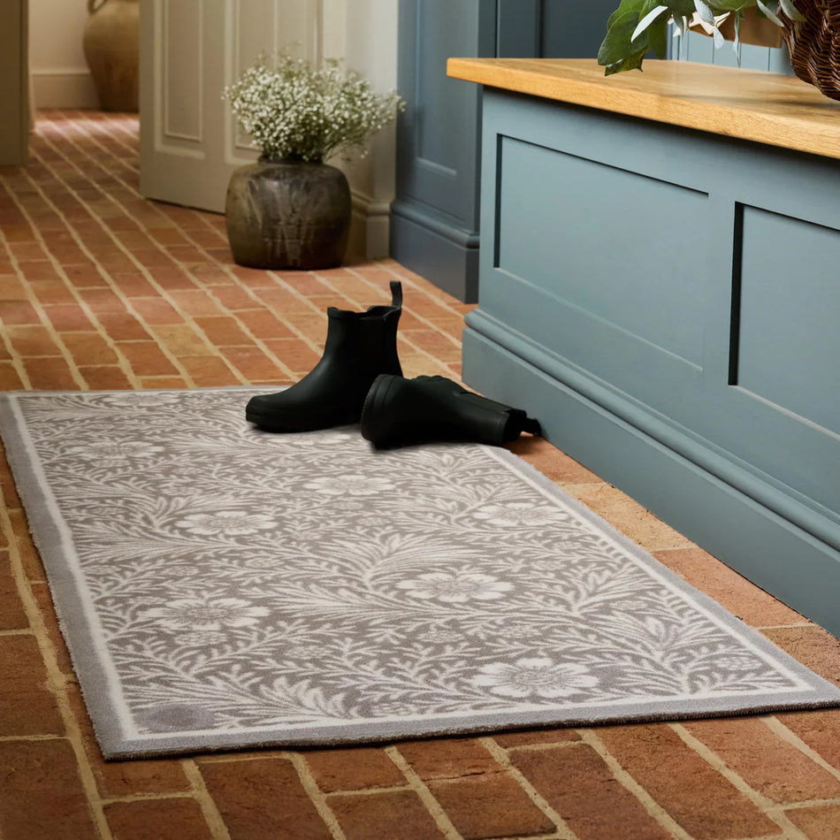 Black boots on a patterned rug in front of a blue cabinet with a wooden top.
