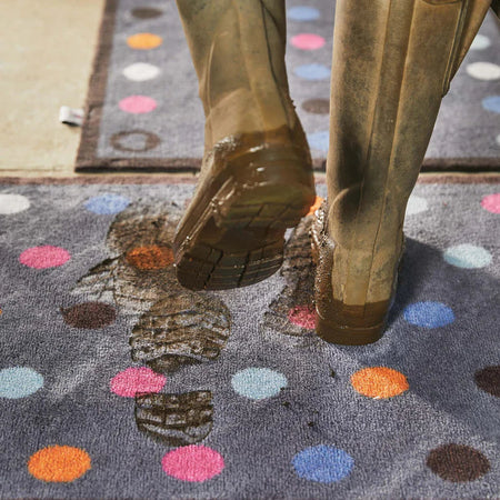 Person stepping onto a colorful polka dot rug with patterned border