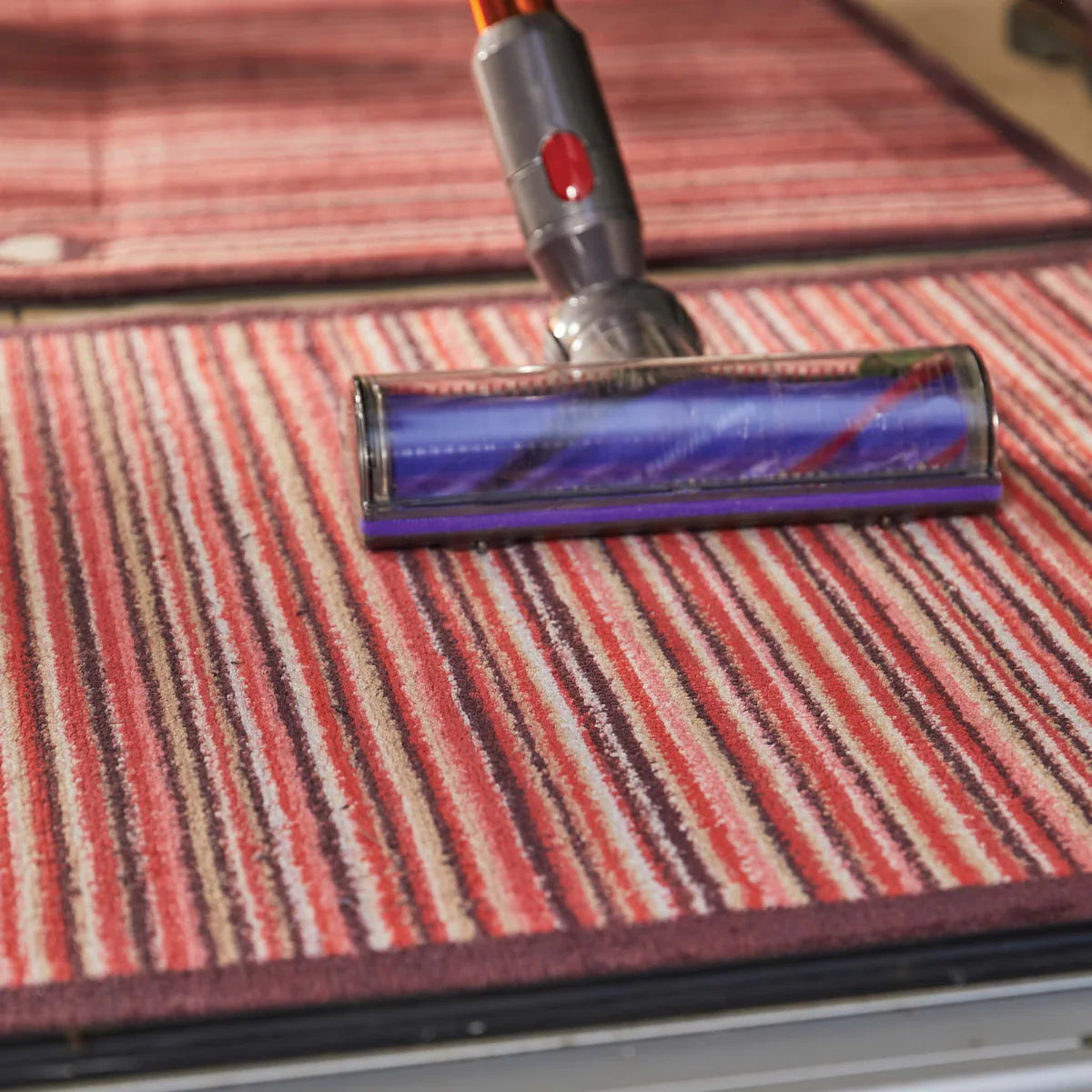 Vacuum cleaner head on a striped carpet