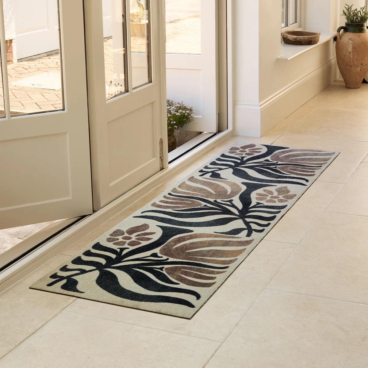 Decorative floral rug on a tiled floor in front of a glass door.