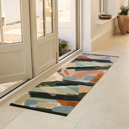Colorful geometric-patterned rug on a tiled floor in a home setting.