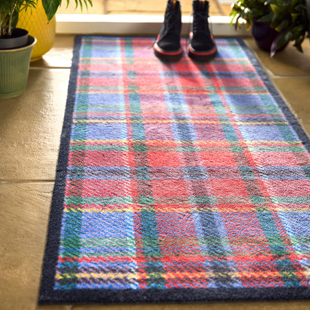 Colorful plaid rug on a wooden floor with shoes at the end