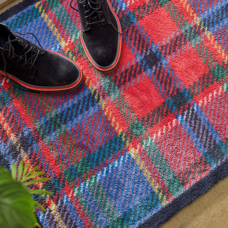 Colorful plaid rug with black shoes on top