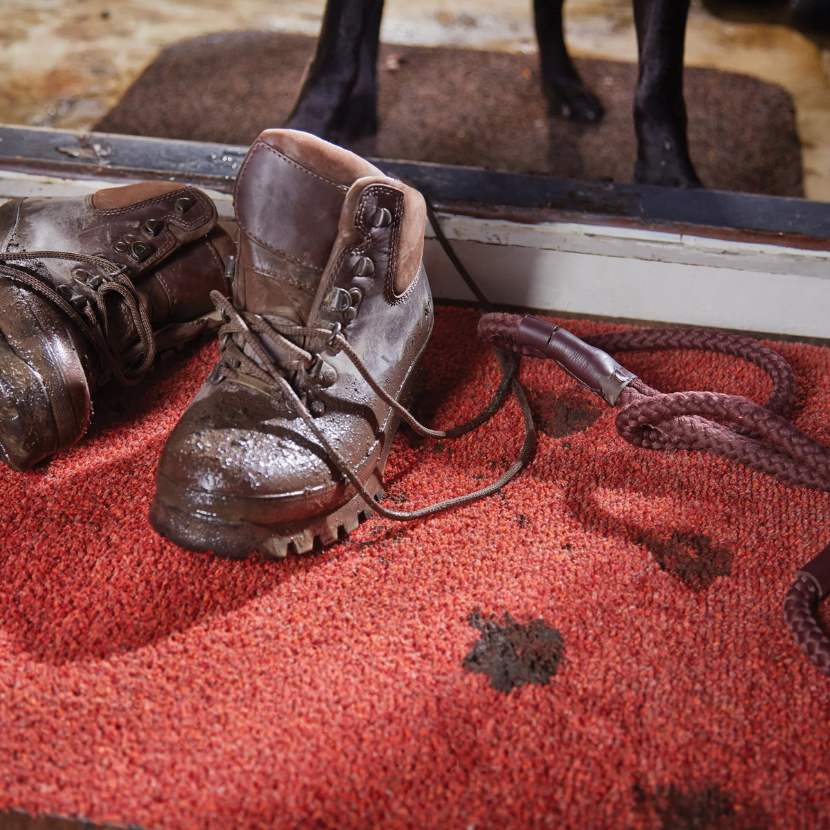 Pair of brown leather boots on a red surface with a blurred background