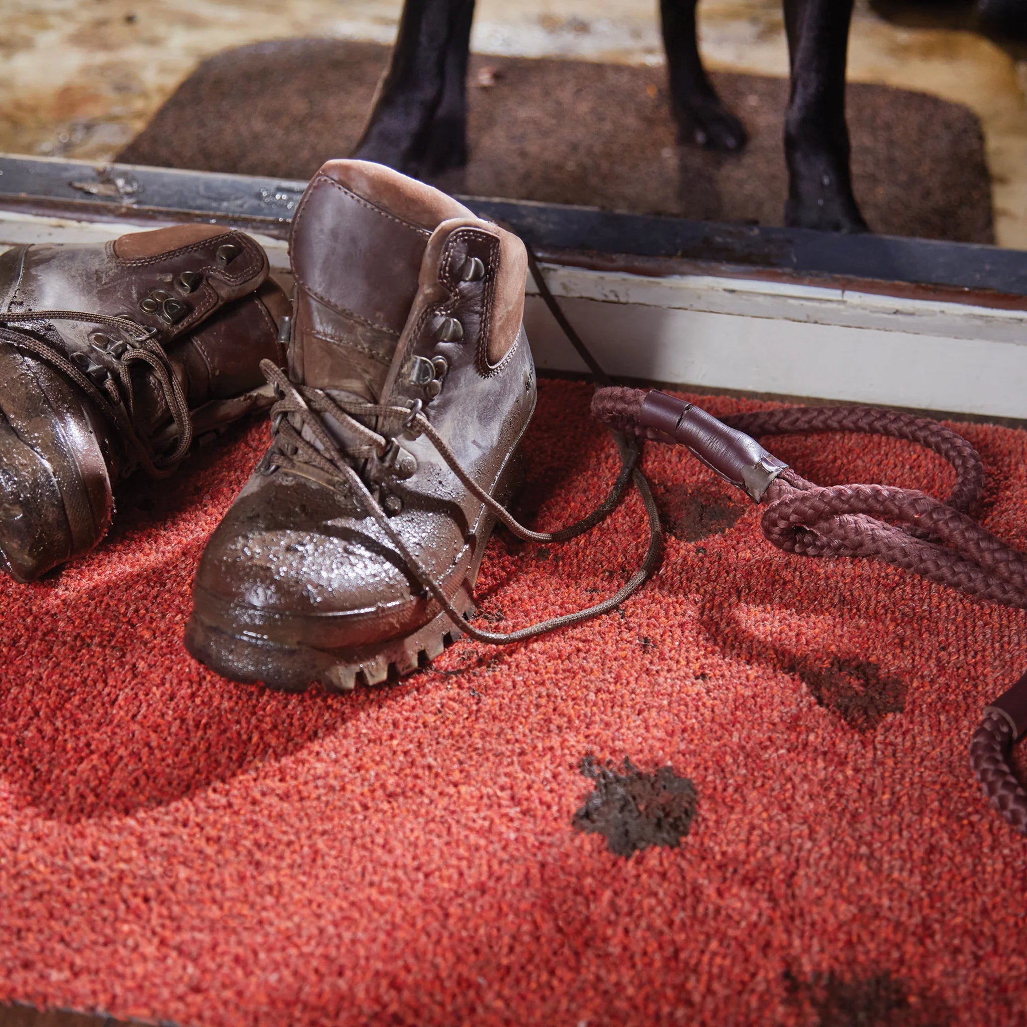 Pair of brown leather boots on a red surface with a blurred background