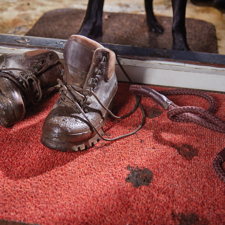 Pair of brown leather boots on a red surface with a blurred background