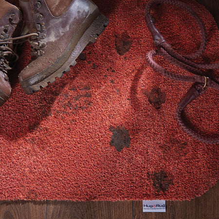 Brown boots on a red textured rug with 'Hugo Rug' label.