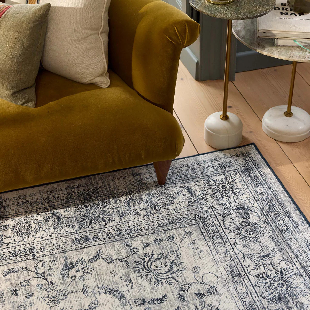 Patterned rug on a wooden floor with a mustard yellow armchair and side table.