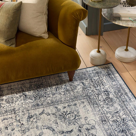 Patterned rug on a wooden floor with a mustard yellow armchair and side table.