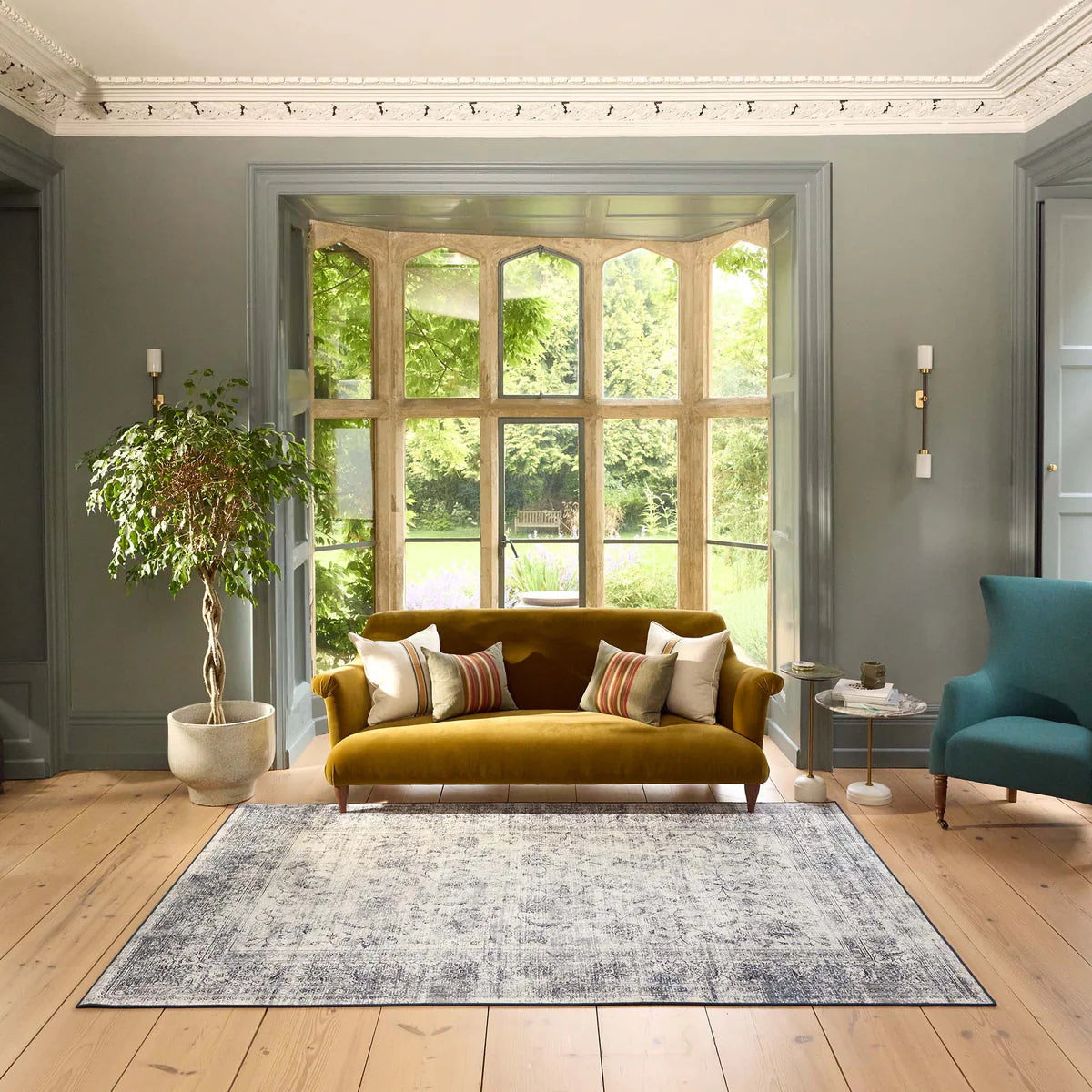 Living room with mustard yellow sofa, patterned rug, and large window
