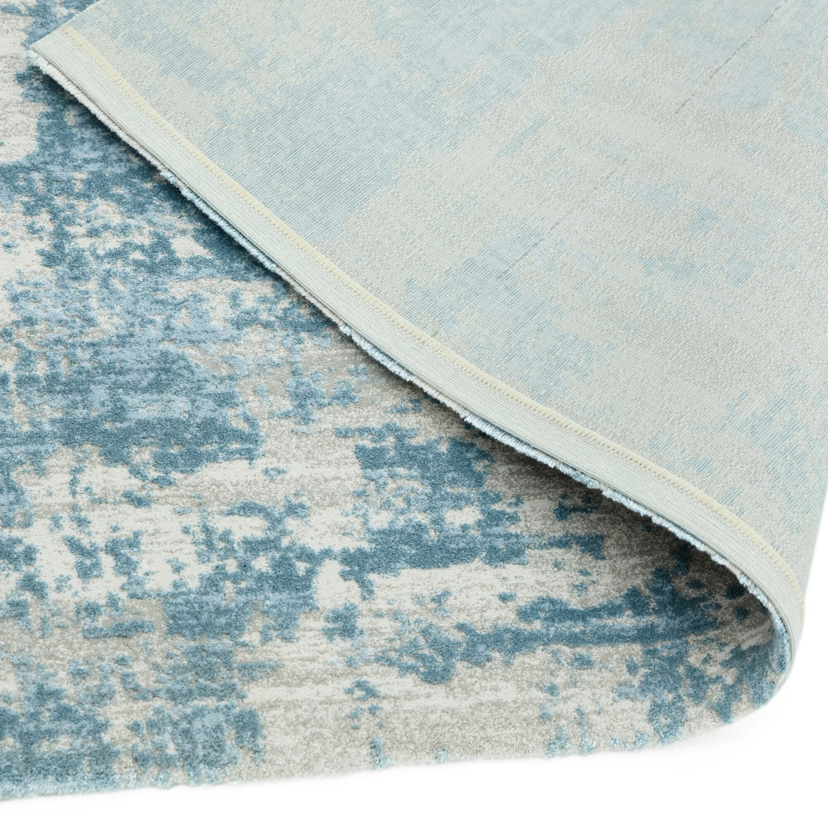 Machine-woven silver-blue rug under natural light showing backing