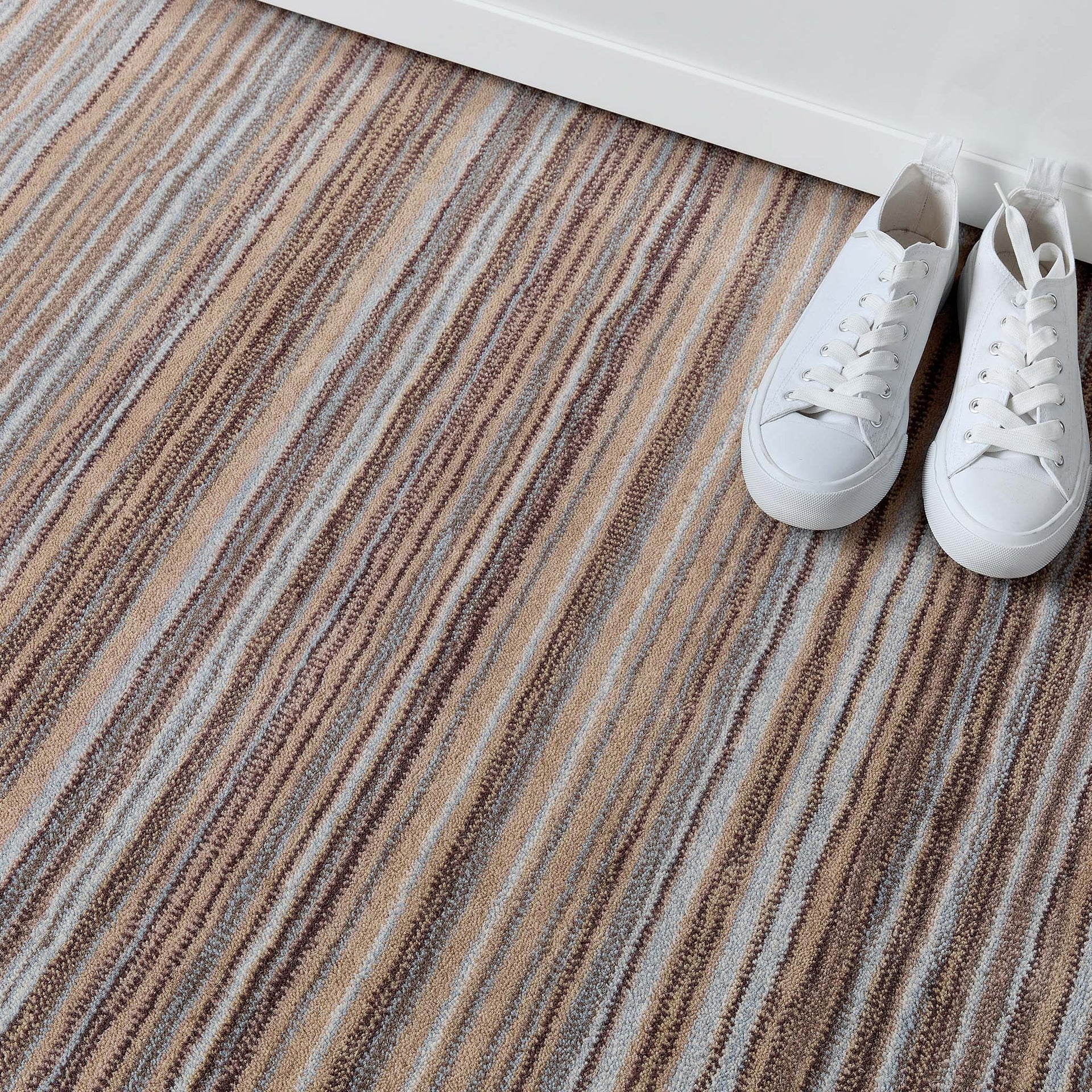 Striped carpet with white sneakers on a white floor