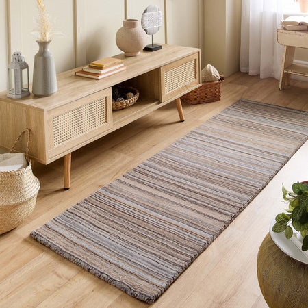 Wooden cabinet with decorative items on a wooden floor with a striped rug.