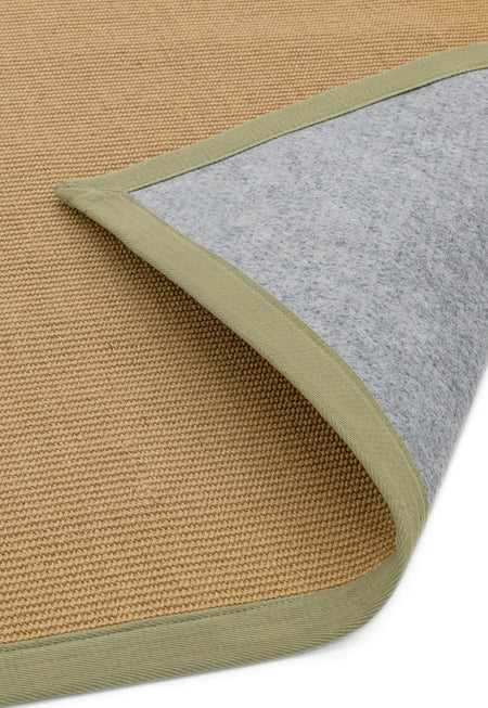 Hand-stitched sage border on neutral rug showing non slip backing